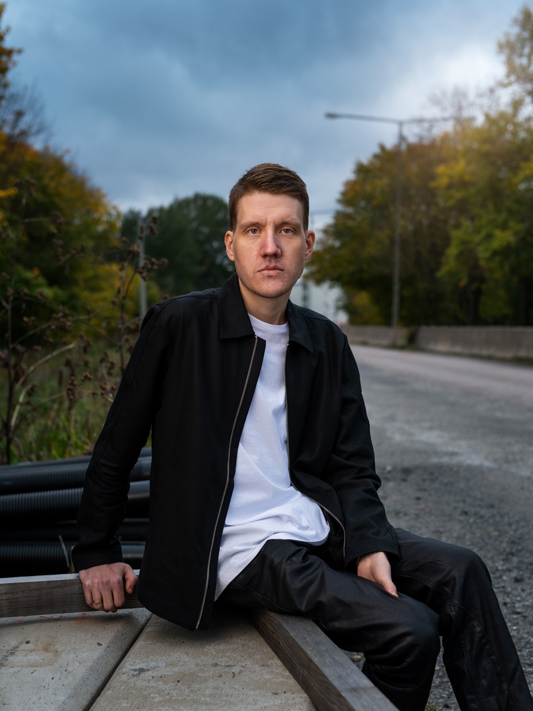 Mikael Yvesand sitting on concrete barrier on empty road