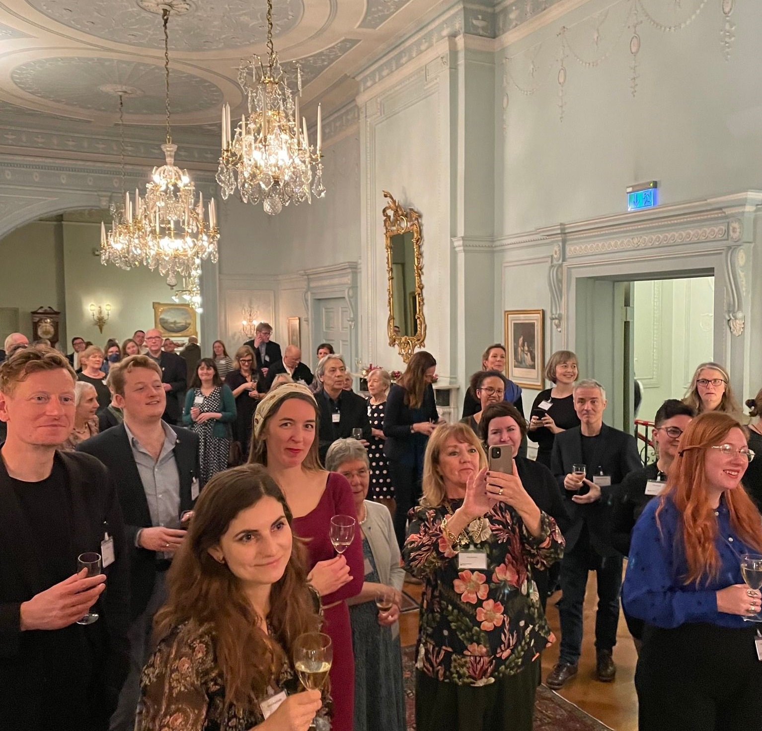 A crowd of people standing in an ornately decorated room for the SELTA anniversary celebrations