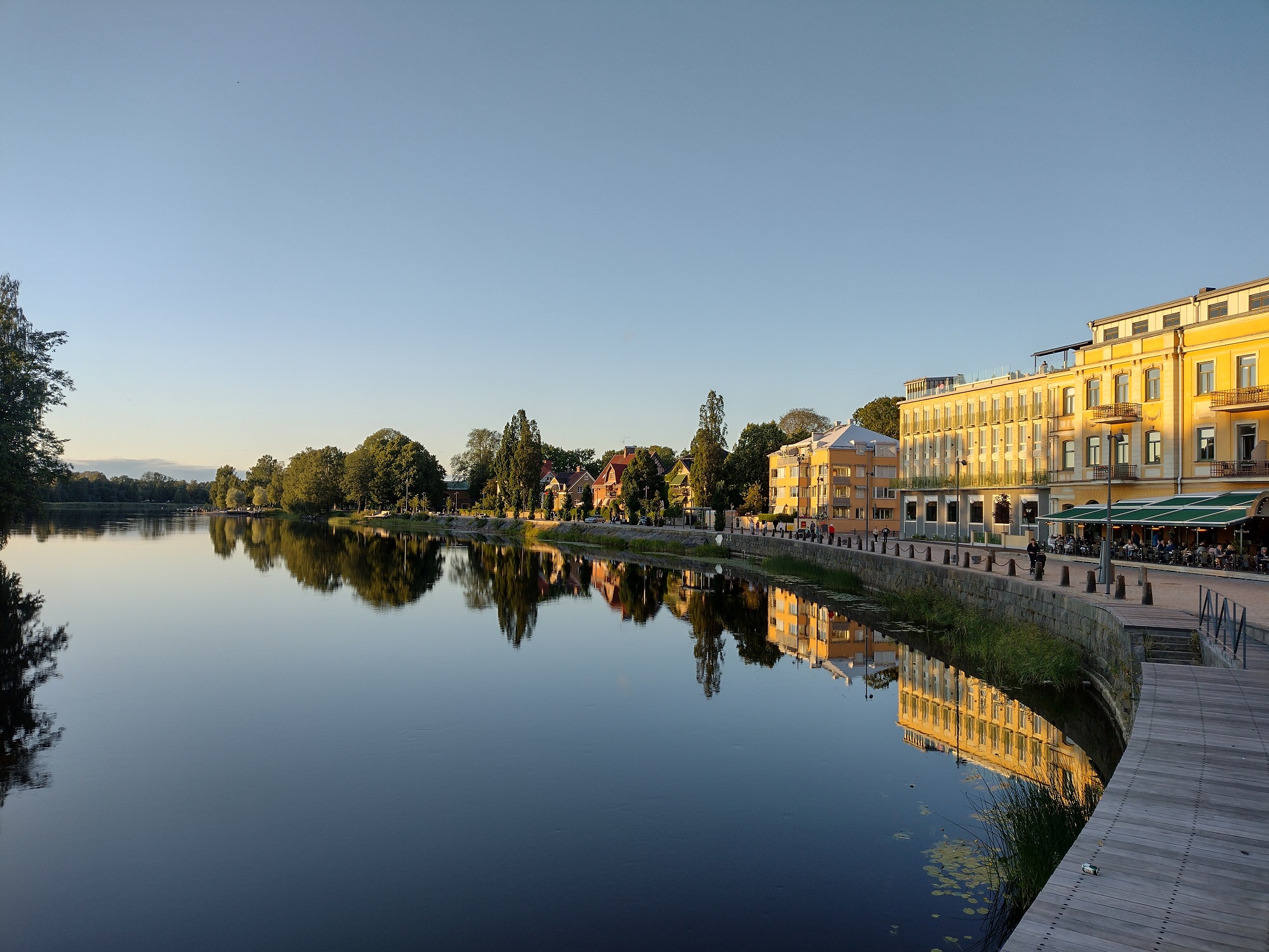 A curving lake waterfront with a mirrorlike surface in the late afternoon sun