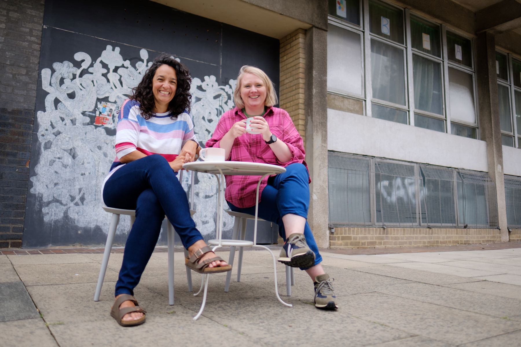 Camila França & Trine Garrett sitting at table in front of Rose Lipman Building.