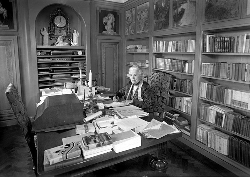 Black and white image of an elderly woman sitting in her study.