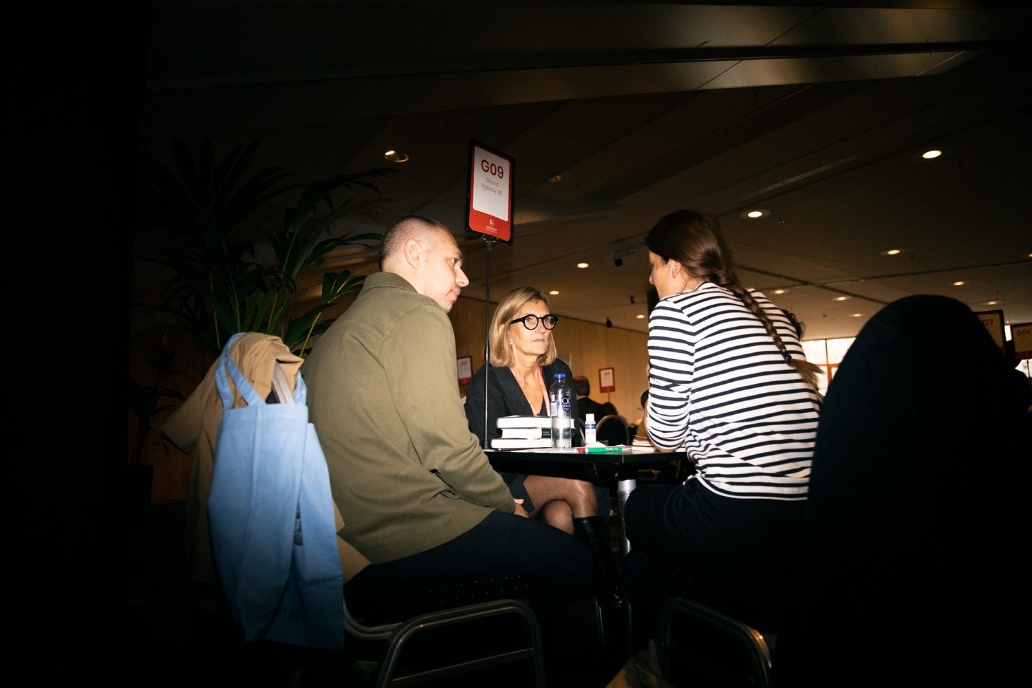 Lena Stjernström wearing glasses and a black dress in a meeting with two clients