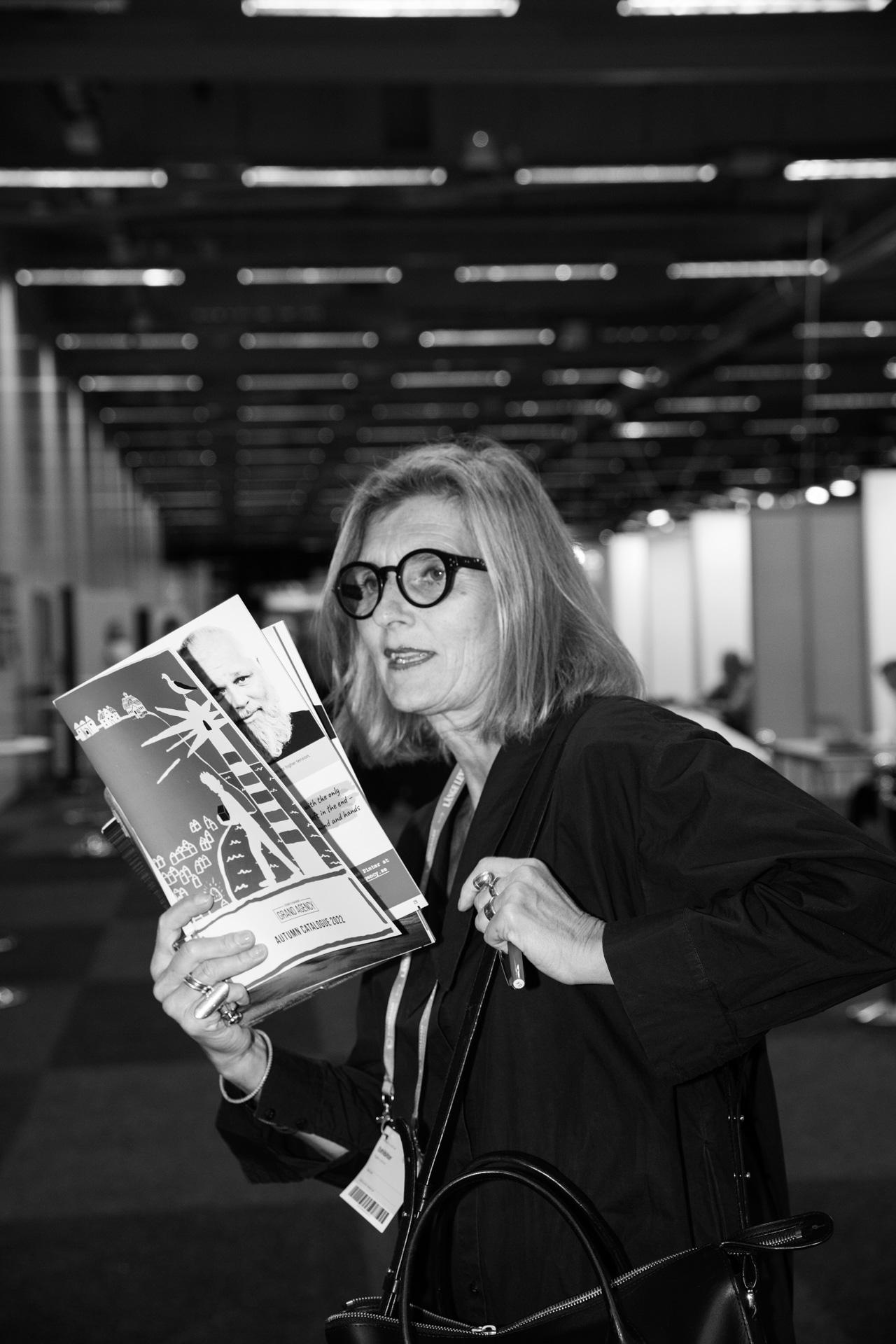 Blond woman in dark dress and glasses holding rights guide