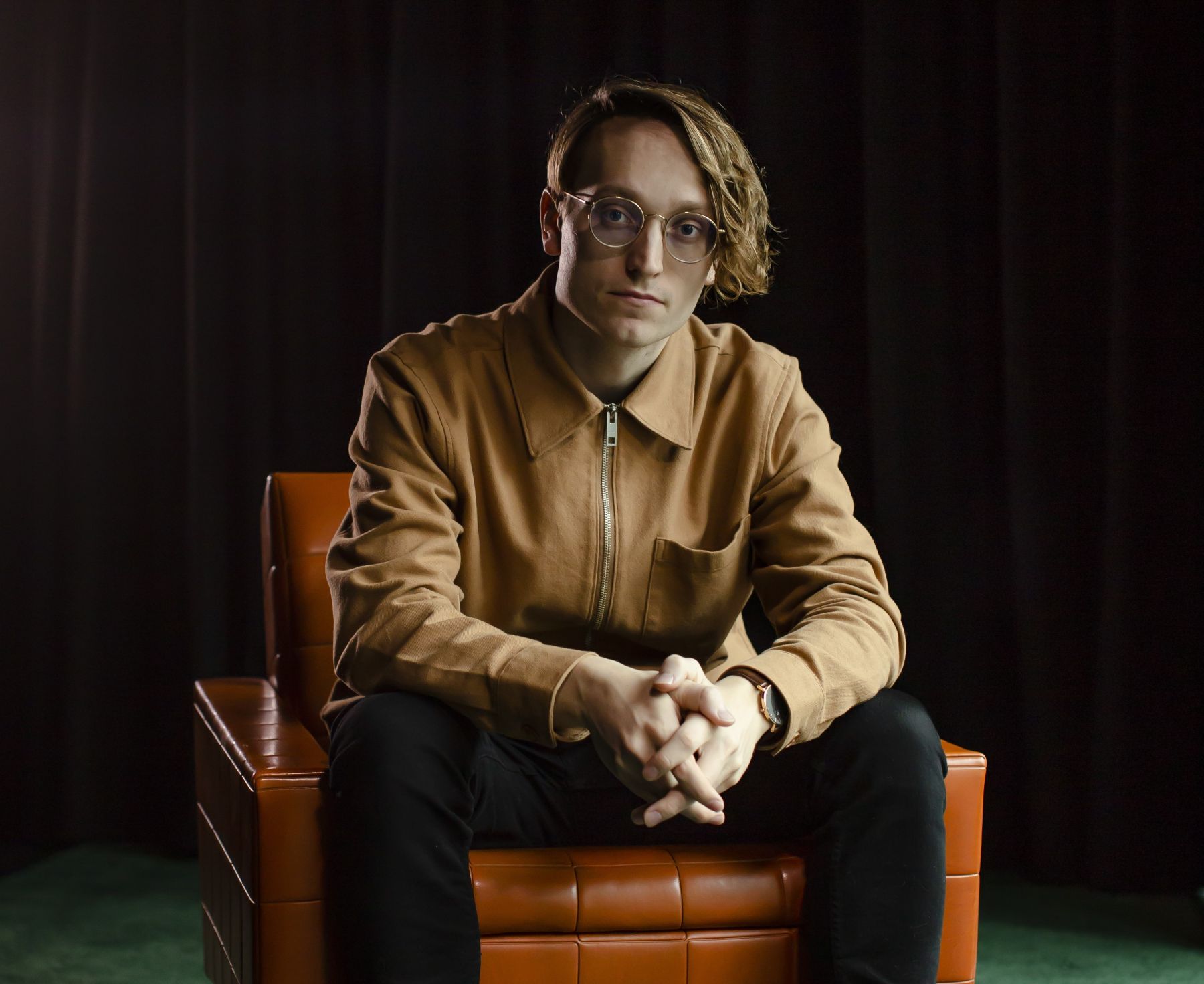 Axel Åhman sitting in leather chair with arms resting on knees