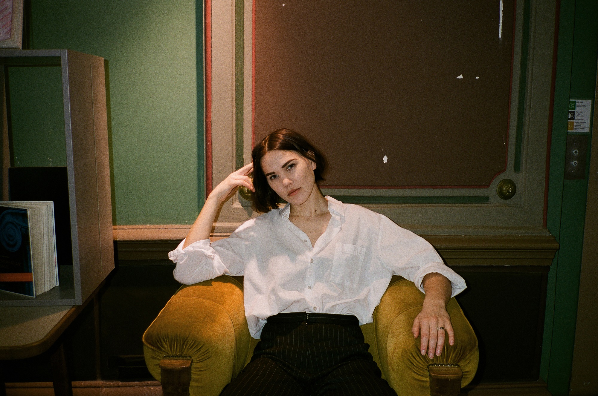 Young woman with short dark hair in a white shirt sitting in an armchair