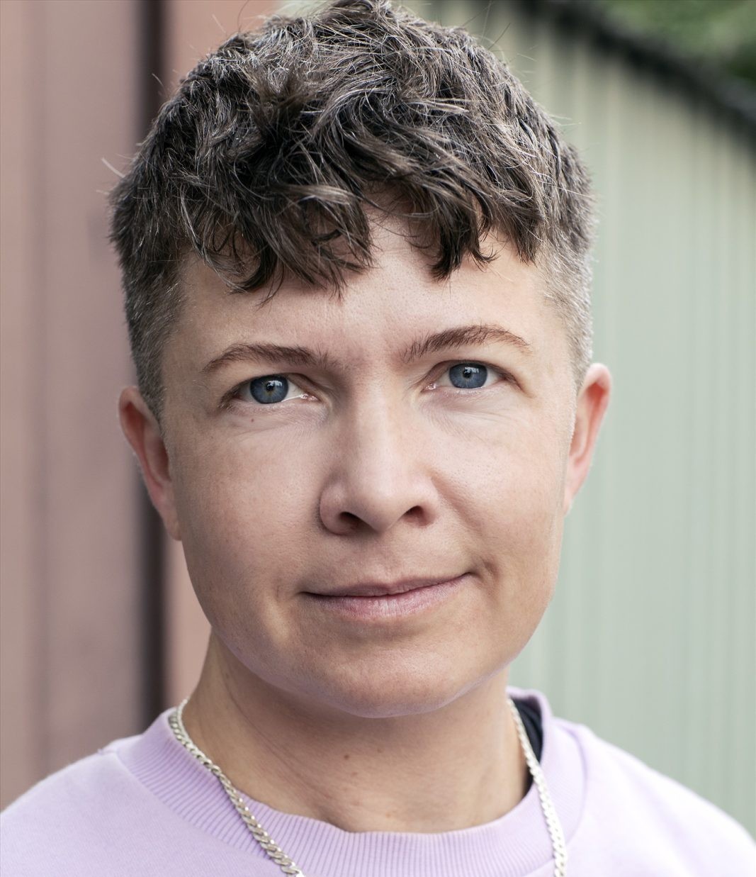 Author photo of Sam Hultin wearing lilac sweatshirt and chain