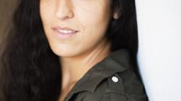 Pooneh Rohi standing by a white wall