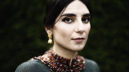 Balsam Karam in beaded necklace and gold earrings