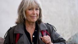 Agneta Pleijel in trenchcoat holding bag