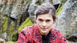 Frida Nilsson in red jacket in front of mossy rocks