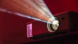 shining LED projector on table against red background
