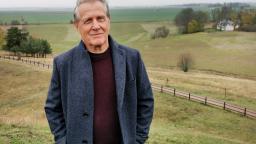 Man in grey jacket with a background of rolling fields