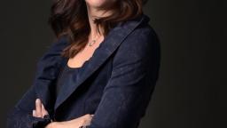 Brown-haired woman in a blazer smiling at the camera.