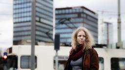 Olivia Bergdahl in red scarf standing in front of tower blocks