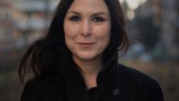 Woman wearing black coat with dark hair swishing in the breeze