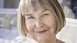 Woman with peppery grey bob smiling at camera
