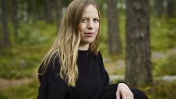 Linda Jones in black top sitting in forest landscape