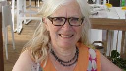 Eivor Martinus smiles at the camera, sitting in a relaxed pose wearing a colourful summer blouse.