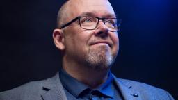 Marcus Rosenlund in blue shirt and grey suit against deep blue background