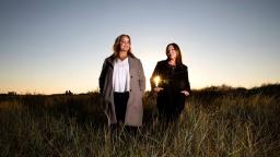 Emmy Abrahamson and Hanna Jedvik standing in long grass at sunset.