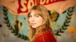 Author photo of Klara Bartilsson in front of colourful mural.