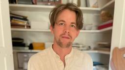 Johan Persson in white shirt standing in front of shelves of boxes.