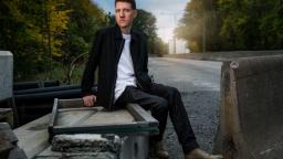 Author portrait of Mikael Yvesand sitting on concrete barrier.