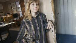 Lisen Adbåge standing by scuffed door in striped top.