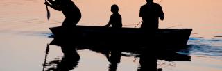 image of silhouette of three figures rowing in open water.